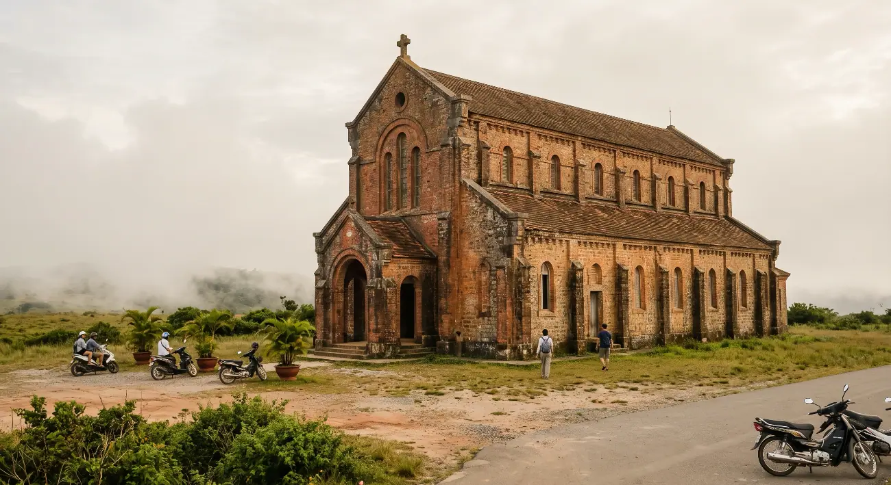 The old brick Catholic church on the Bokor plateau in low cloud, a handful of visitors and their scooters at the door, short grass and scrub around it